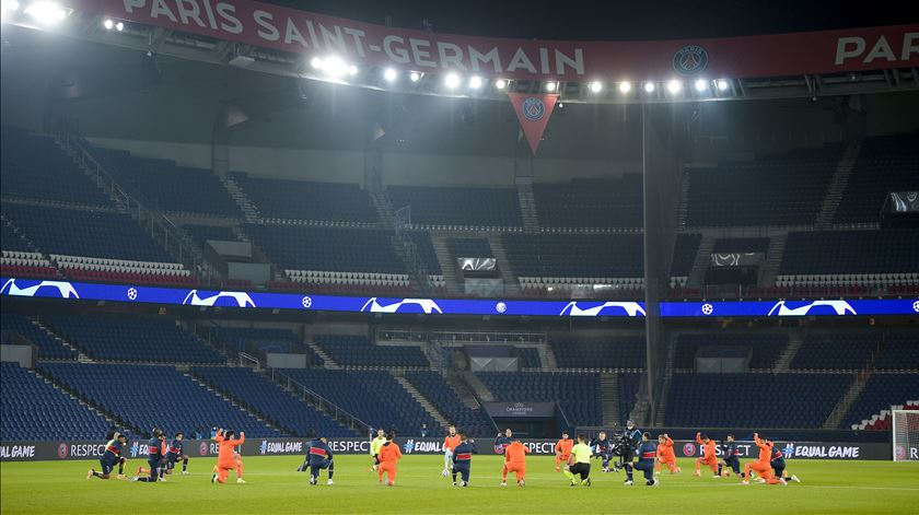 Jogadores de PSG e Basaksehir e árbitros de joelhos. Foto: JB Autissier/Reuters