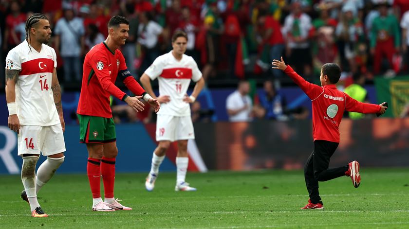 Criança invade jogo de Portugal com a Turquia para abraçar Cristiano Ronaldo. Foto: Friedemann Vogel/EPA