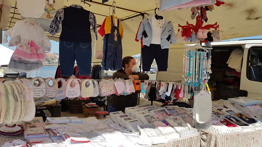 Comerciante usa máscara e luvas na feira da Afurada, em Vila Nova de Gaia, que continua a atrair clientes apesar do surto de coronavírus. Foto: Maria João Cunha/RR