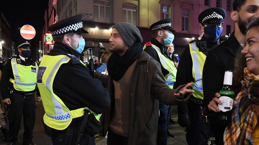 Um agente policial afasta jovens do bairro londrino de Soho com o início do novo período de confinamento. Foto: Andy Rain/EPA