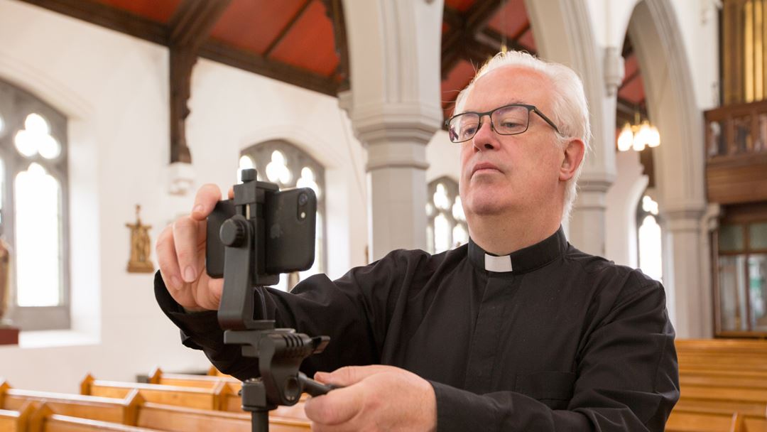 Padre prepara o telemóvel para transmitir as celebrações da Páscoa via Facebook numa igreja em Glasgow, Escócia. Foto: Robert Perry/EPA